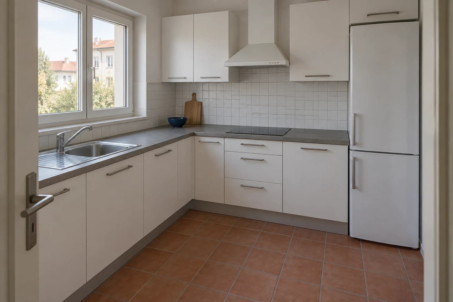 Reference L-shaped kitchen with white cabinetry, a grey counter, white tile backsplash and terracotta floor.